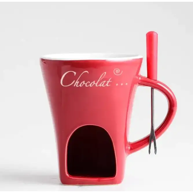 Red ceramic chocolate fondue mug with white cursive ’chocolat...’ inscription and a built-in compartment, featuring an integrated red-handled metal fork.