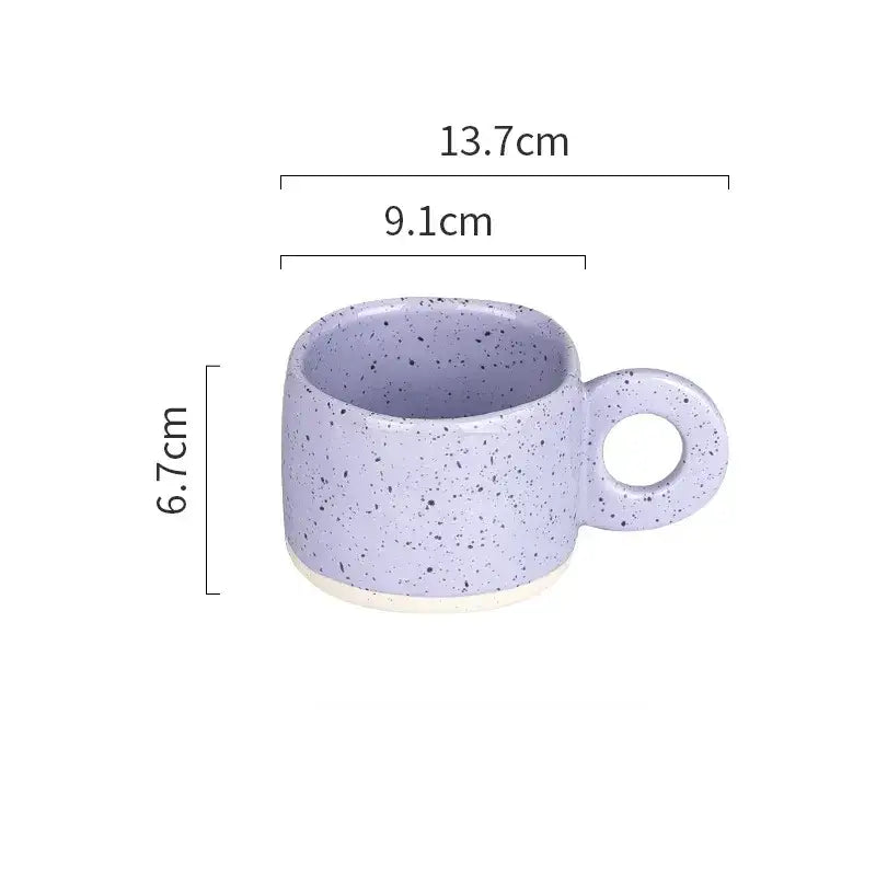 A lavender speckled ceramic mug with a circular handle and white base.
