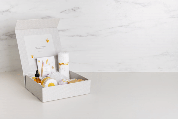 White gift box with gold accents, containing a curated set of bath and body products.