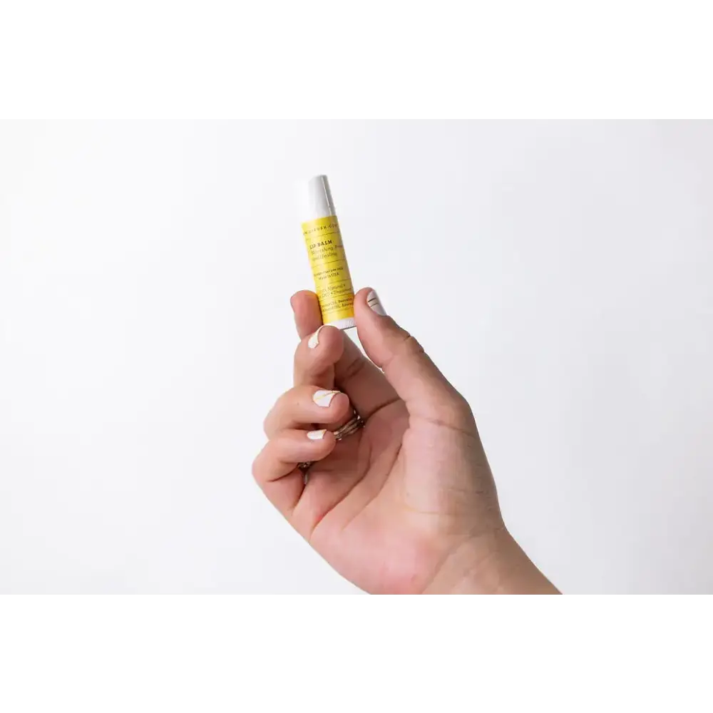 A sleek, cylindrical tube of yellow-labeled lip balm with a white cap.