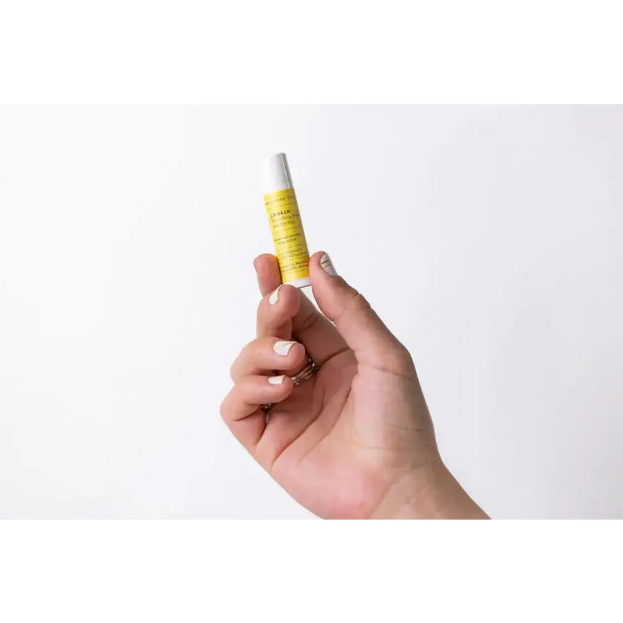 A sleek, cylindrical tube of yellow-labeled lip balm with a white cap.