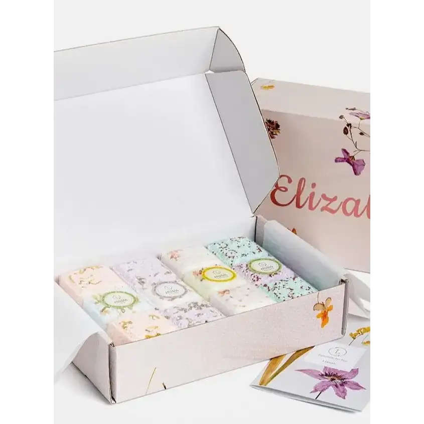 A delicate set of six floral-patterned soap bars nestled in a soft pink gift box with butterfly and botanical illustrations.