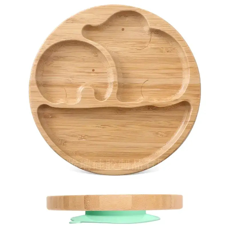Round bamboo baby plate with carved elephant design and a green silicone suction base.