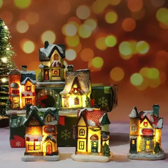 A collection of miniature illuminated christmas village houses with snow-dusted roofs and glowing windows, crafted from painted resin or plastic.