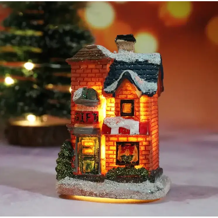 A warmly lit miniature christmas gift shop figurine with red brick walls, a snow-dusted roof and windows glowing from internal lights.