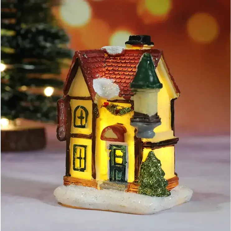 A warmly lit miniature christmas village house with a red tiled roof, yellow walls, and green accents.