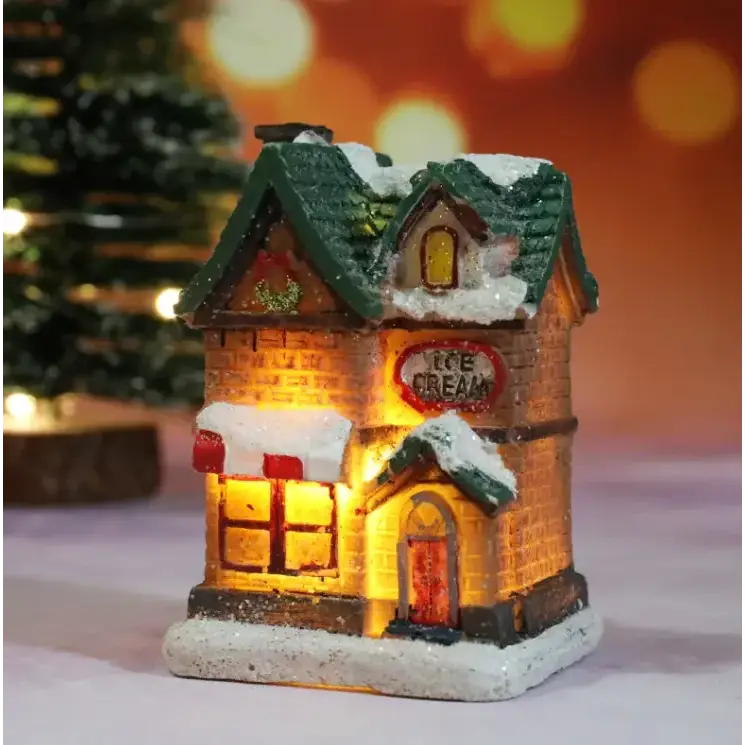 A miniature illuminated ice cream shop figurine with a green roof, brick facade, and glowing windows.