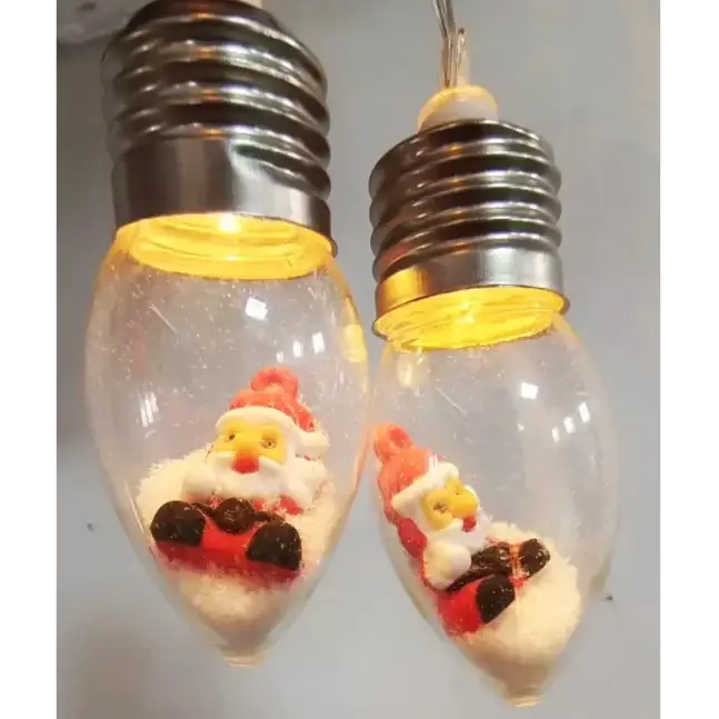 Clear glass christmas light bulbs with silver screw bases, each containing a miniature santa claus figurine in red and white attire sitting on a bed of faux snow.