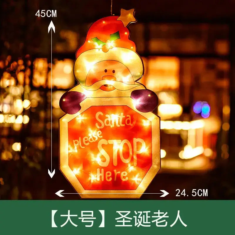 A glowing, illuminated christmas santa claus decoration with a red hat and purple gloves holding an octagonal ’stop’ sign that reads “santa please stop here,” featuring warm led lights within its translucent body.