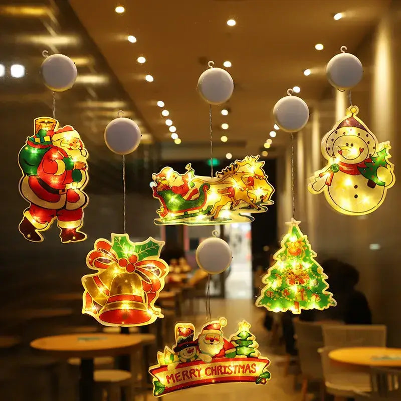 A set of illuminated christmas-themed hanging decorations featuring santa, a sleigh with reindeer, a snowman, bells, and trees in glowing reds, greens, golds, and whites.
