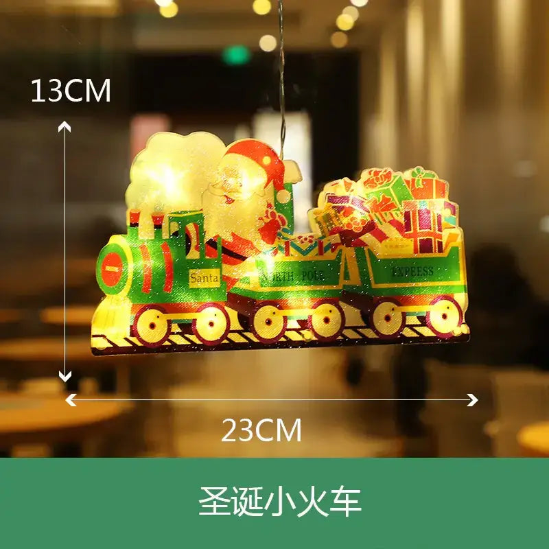 A festive green and red illuminated christmas train ornament featuring santa claus driving a locomotive with ’north pole express’ written on the side, carrying colorful gift boxes in its cargo car.