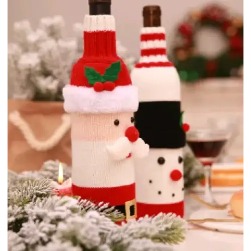 Red and white knitted santa claus bottle cover with green holly, red nose, and black belt.