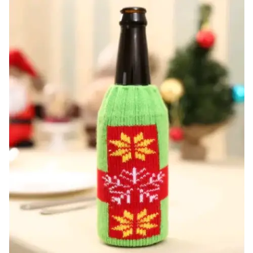 Green knitted bottle sleeve with red and yellow snowflake patterns.