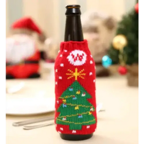 Red knitted beer bottle cozy with a green christmas tree and gold star design.