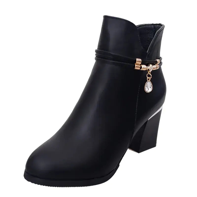 Black faux leather ankle boot with a chunky heel and a decorative gold-toned buckle featuring a dangling crystal teardrop charm.