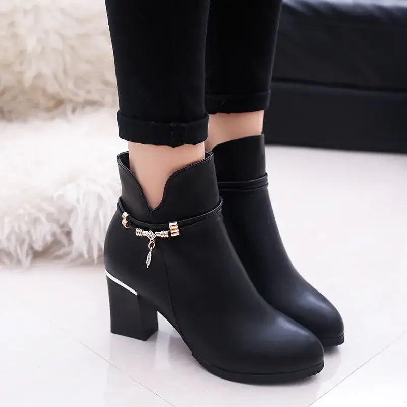 Black ankle boots with a chunky heel and decorative gold-toned buckle detail.