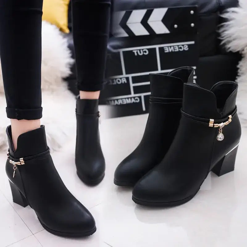 Black leather ankle boots with gold-tone buckle accents and a chunky heel.