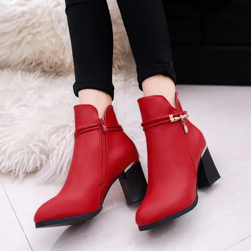 Red leather ankle boots with a chunky black heel and gold-tone buckle detail.
