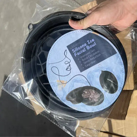 Black silicone facial ice bowl with a sleek, flexible design and a clear plastic packaging label featuring product benefits.
