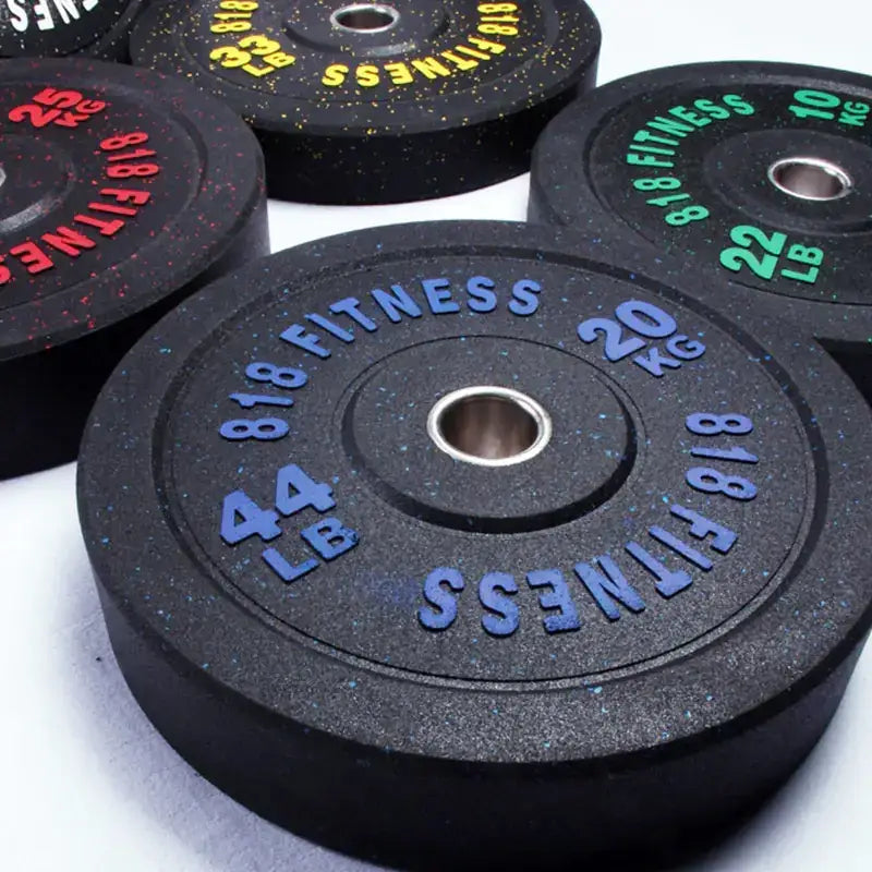 Black rubber weight plates with blue, red, and green lettering indicating weights like 44 lb or 20 kg.