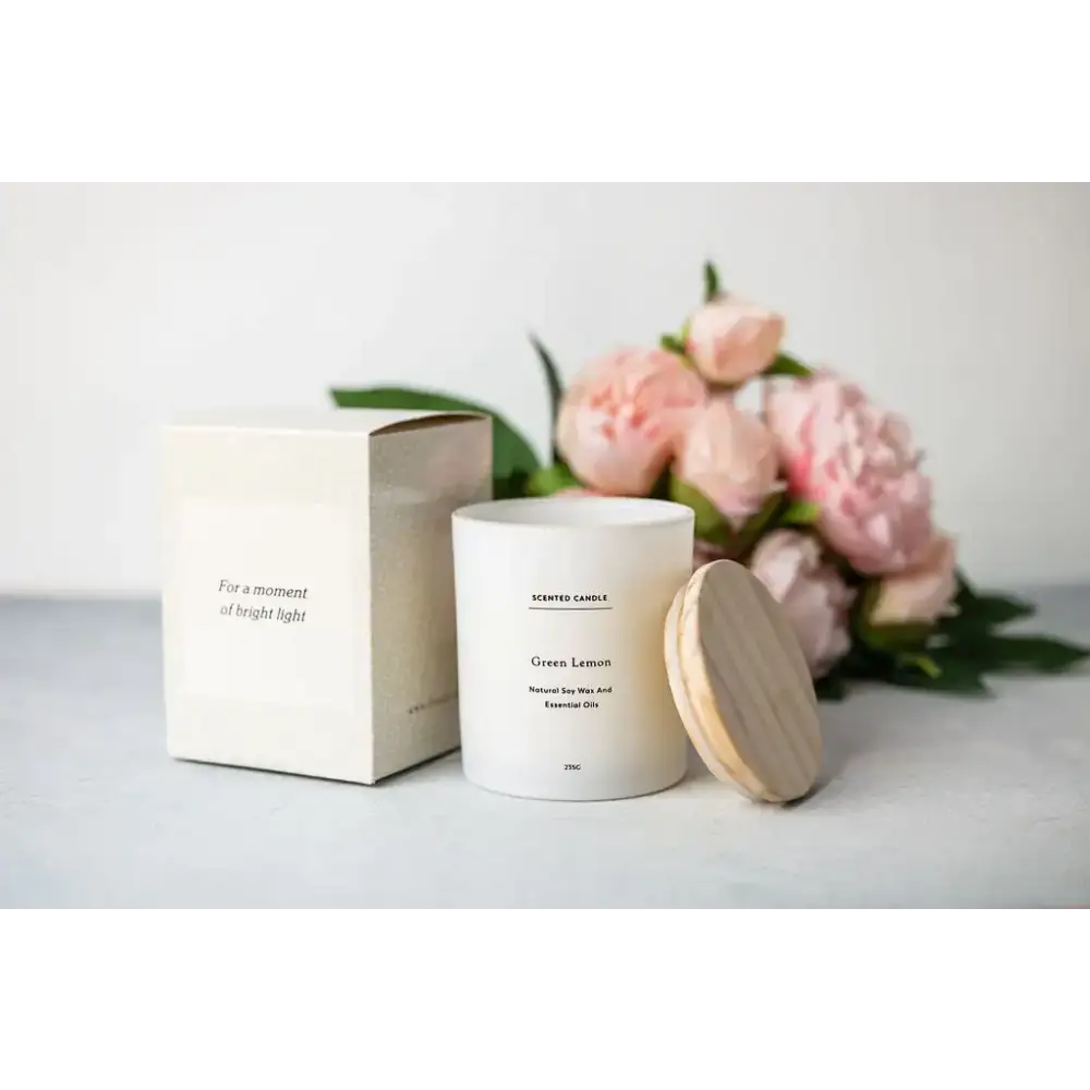 White cylindrical scented candle with a wooden lid, labeled ’green lemon’ and made of natural soy wax.