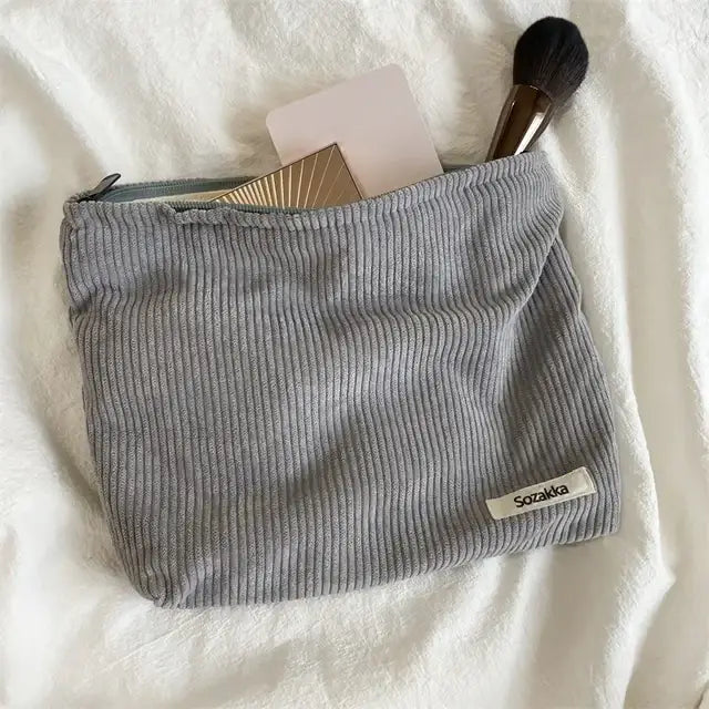 Gray corduroy makeup pouch with a small white label reading ’sozakka’ on the corner