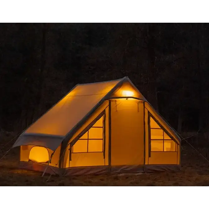 A warmly lit, beige canvas tent with a triangular roof and multiple windows.