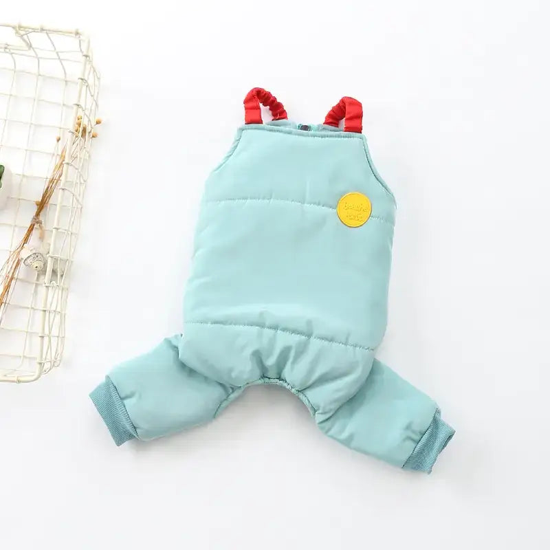 Light blue quilted dog snowsuit with red elastic straps and a yellow circular patch.