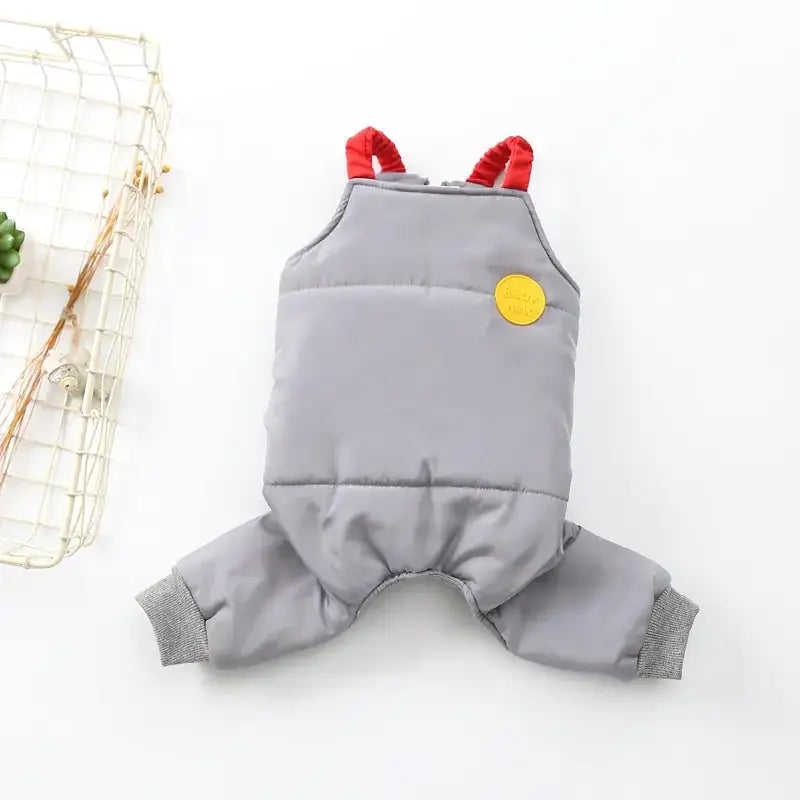 Gray quilted pet overalls with red elastic straps and a yellow circular patch on the chest.
