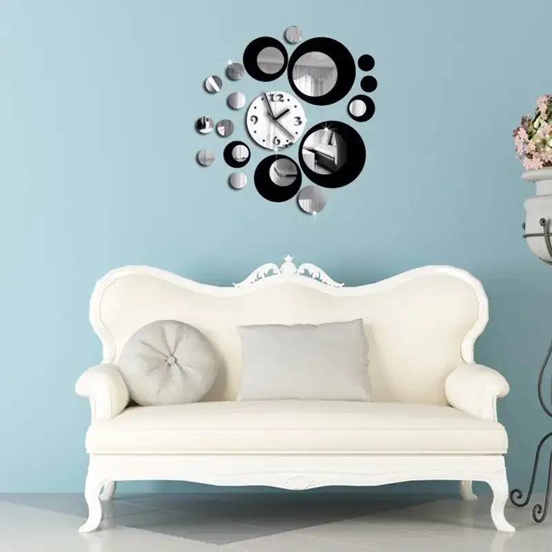 A modern, circular wall clock with a silver face and black numerals is surrounded by an arrangement of various-sized black and mirrored circles.