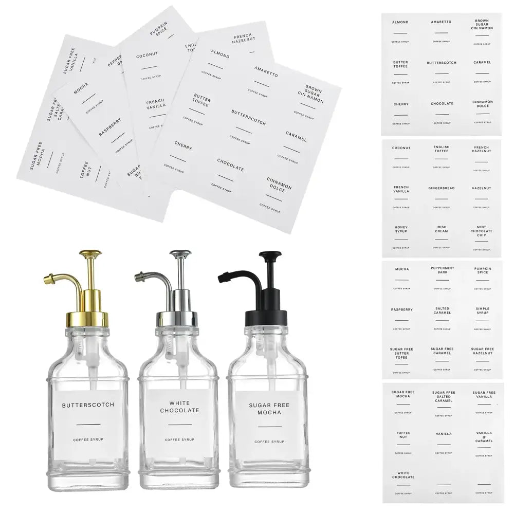 Three clear glass syrup dispensers with gold, silver, and black pump tops.