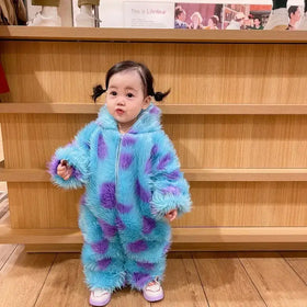 A child wearing a fluffy, light blue and purple patterned one-piece costume with long sleeves and legs.