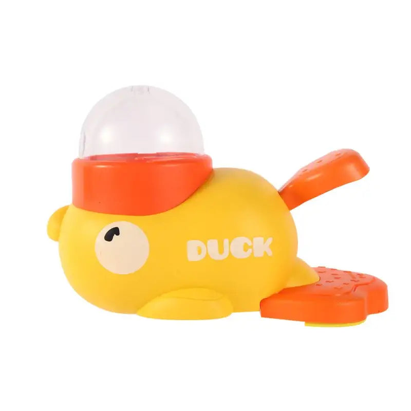 Yellow rubber duck toy with orange accents and a clear dome on its head, featuring the word ’duck’ in white lettering.