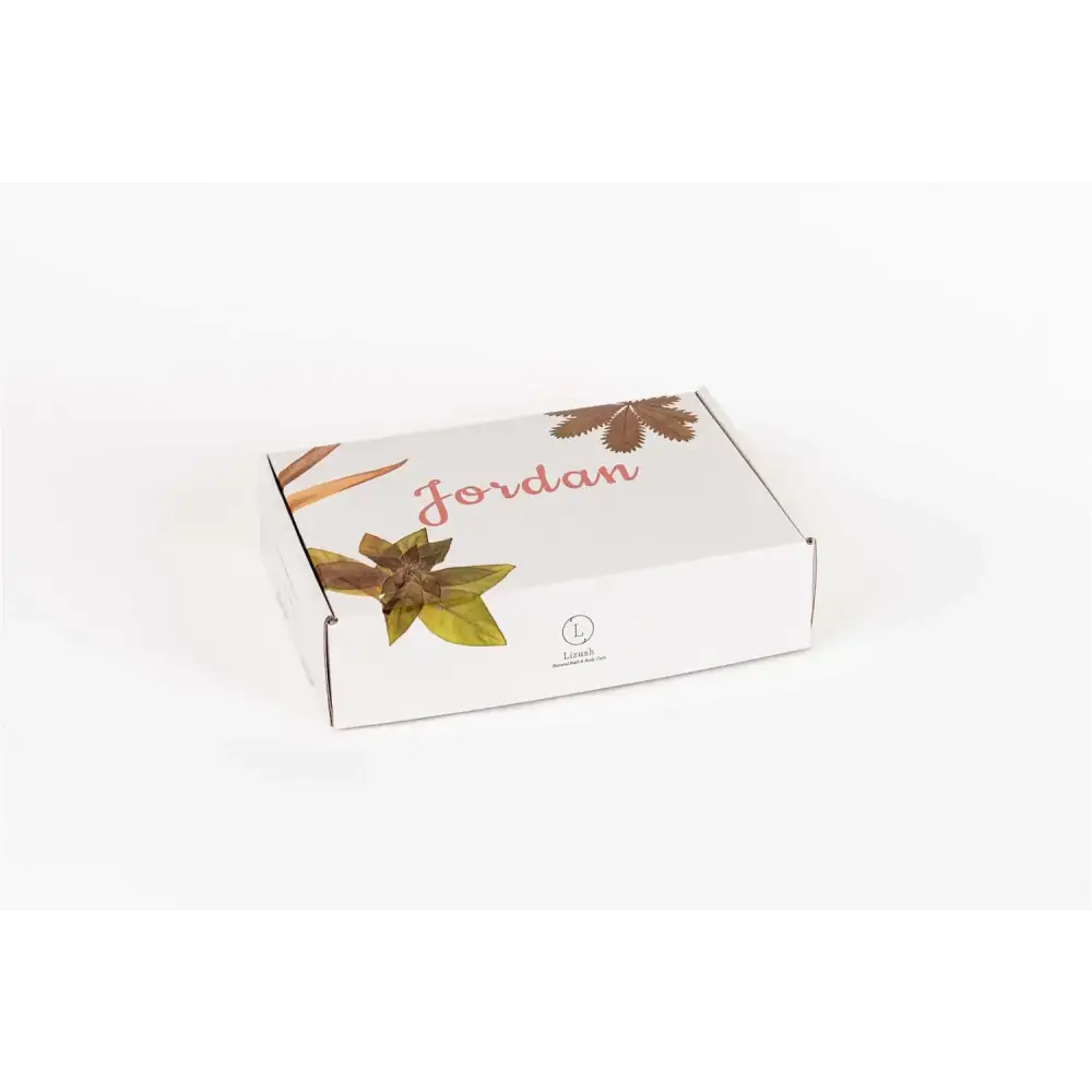 White rectangular box with ’jordan’ printed in pink cursive and illustrated brown and green leaves, featuring a small circular logo for léon’s.