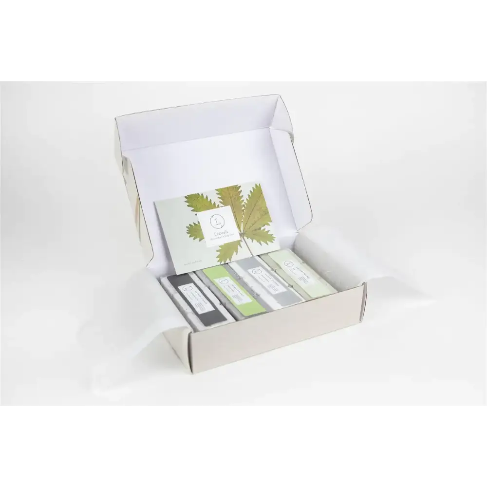 A set of four rectangular soap bars in a minimalist white box, each wrapped with sleek labels and arranged neatly inside.