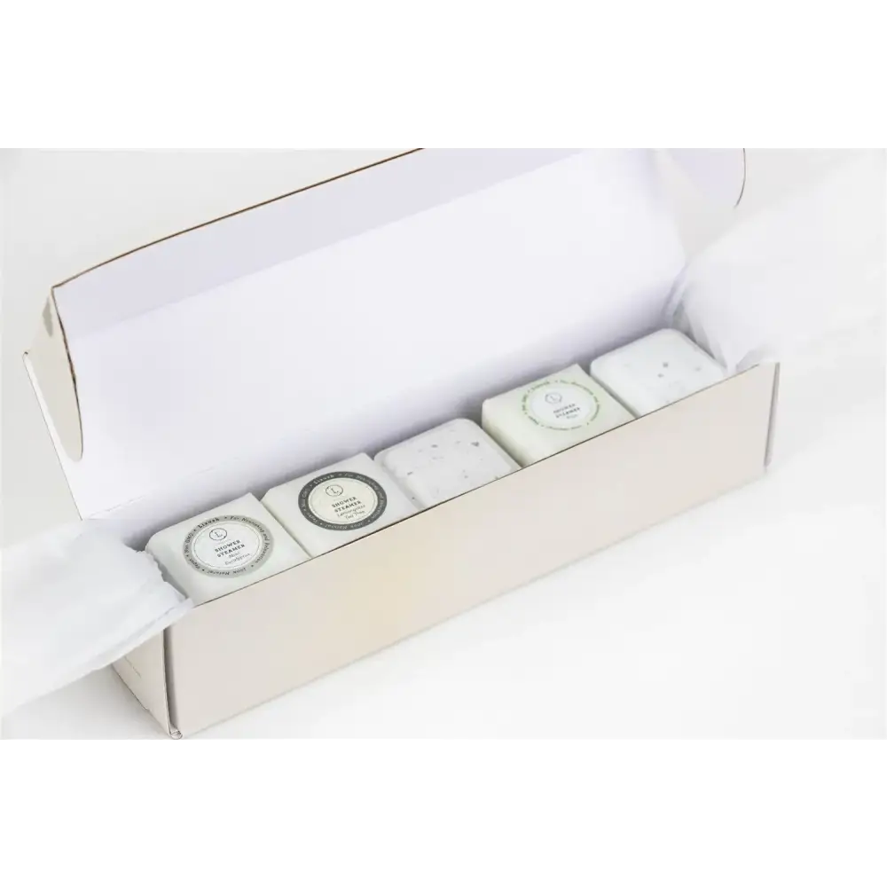 White rectangular bars of soap with circular labels, nestled in a minimalist off-white gift box.