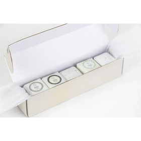 White rectangular bars of soap with circular labels, nestled in a minimalist off-white gift box.