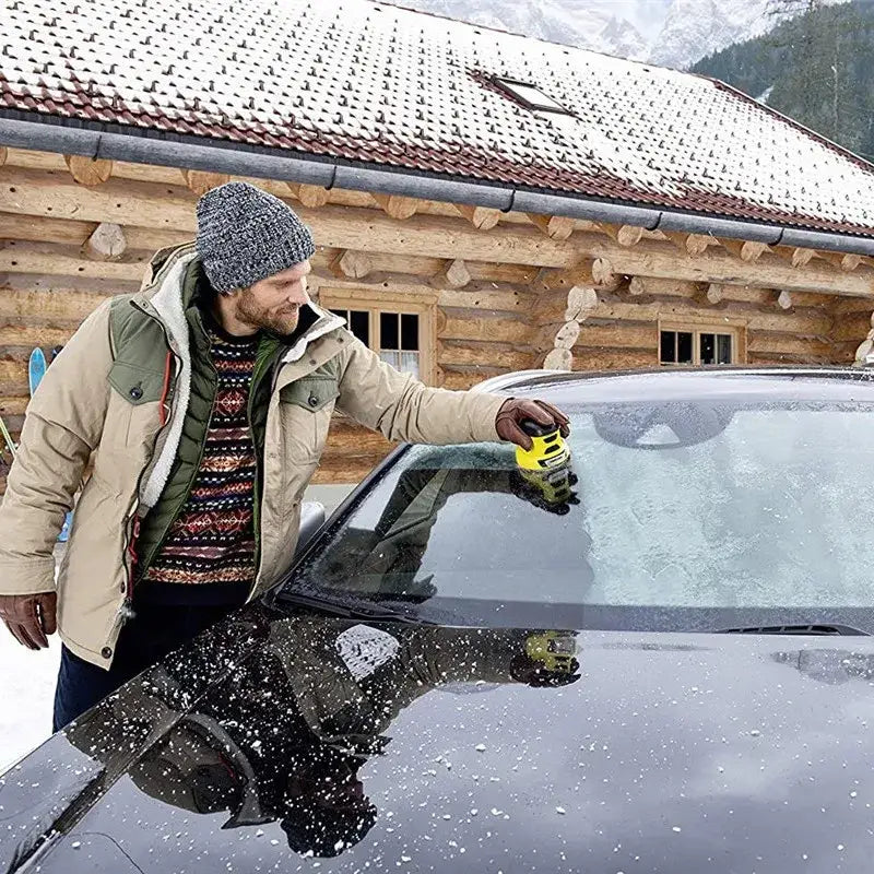 Yellow ice scraper with black grip being used on a car windshield