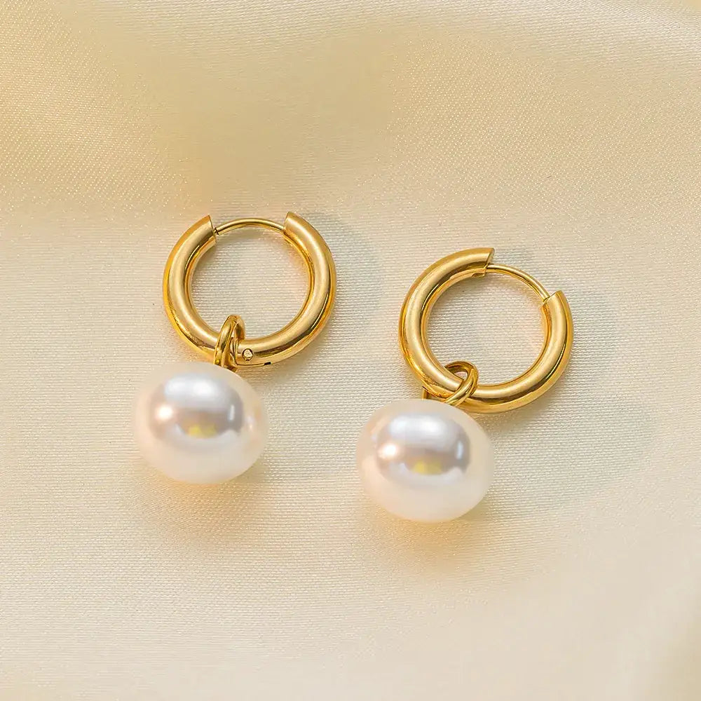 Gold hoop earrings with dangling white pearls.