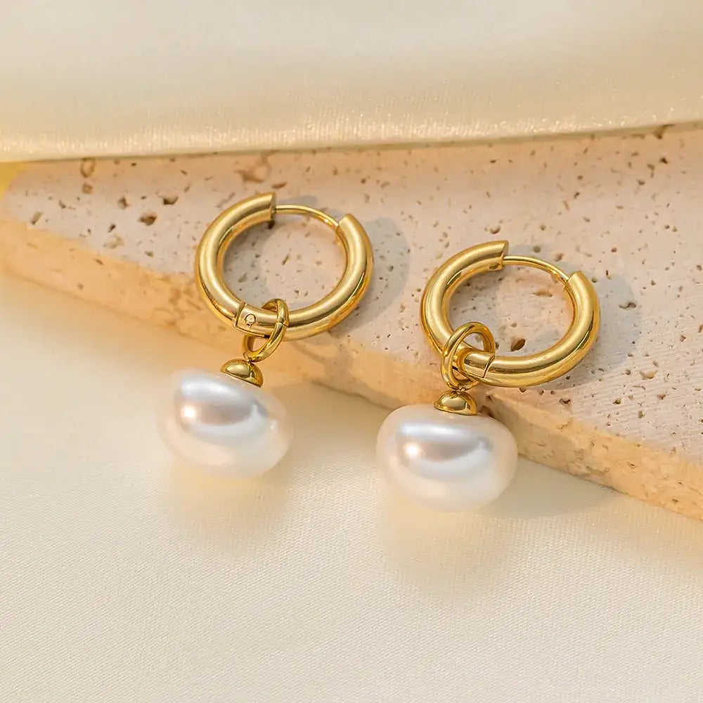 Gold hoop earrings with dangling white pearls.