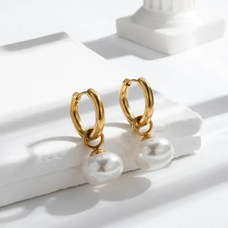 Gold hoop earrings with dangling white pearls.