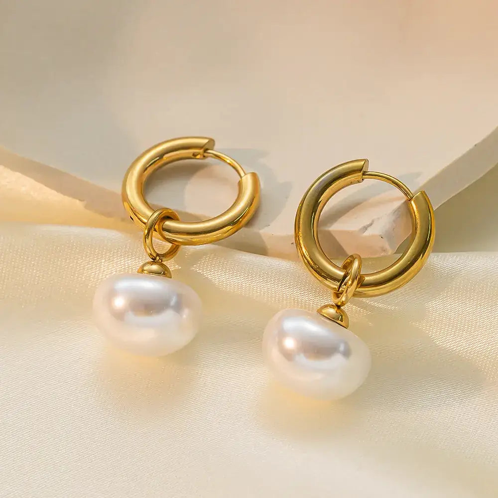 Gold hoop earrings with dangling white pearls.