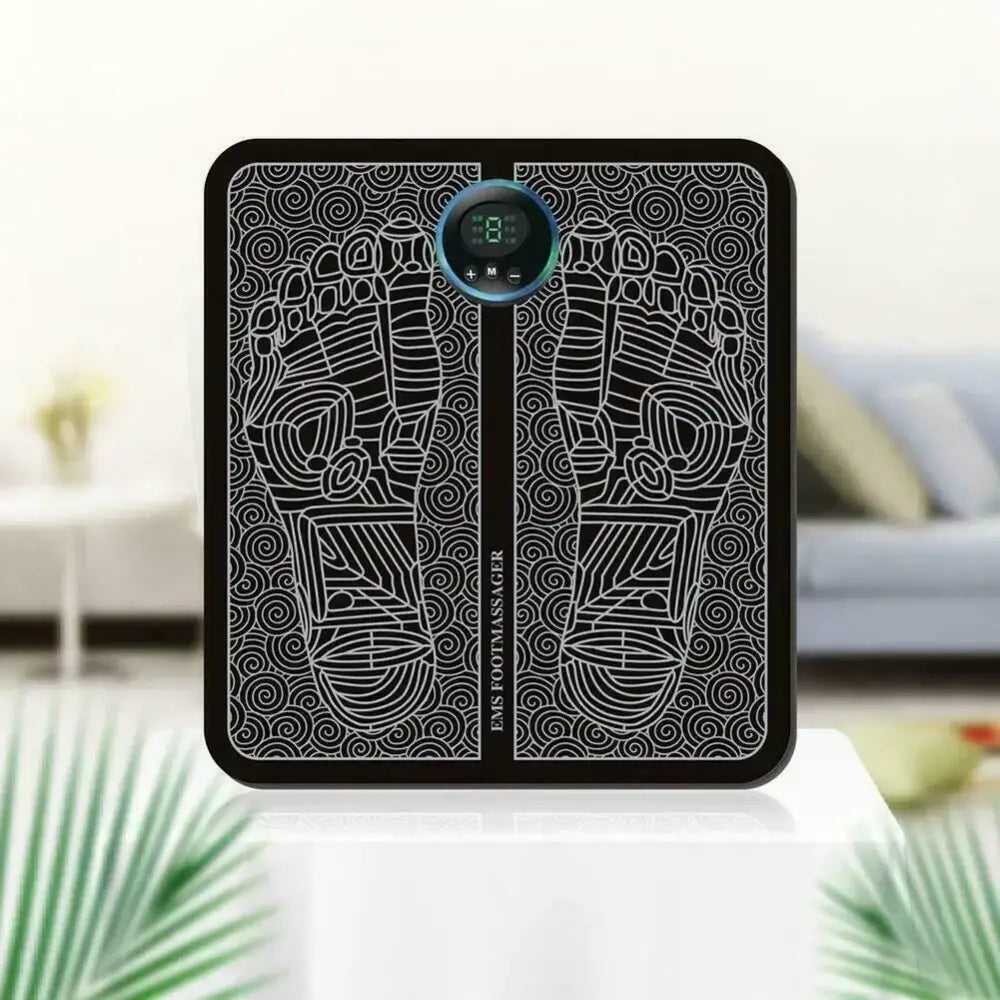 Black rectangular ems foot massager with silver line art depicting feet and swirling patterns, featuring a circular digital display at the center.