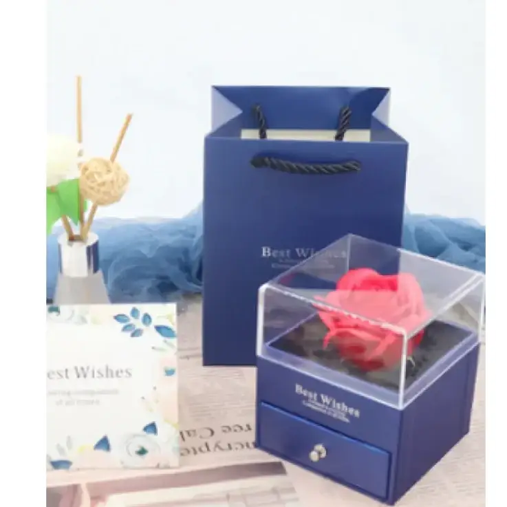 A vibrant pink preserved rose nestled inside a clear acrylic display box with a navy blue base and drawer.