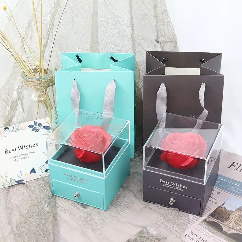 A vibrant red preserved rose nestled inside a clear acrylic box with a small drawer, presented in an elegant gift set.