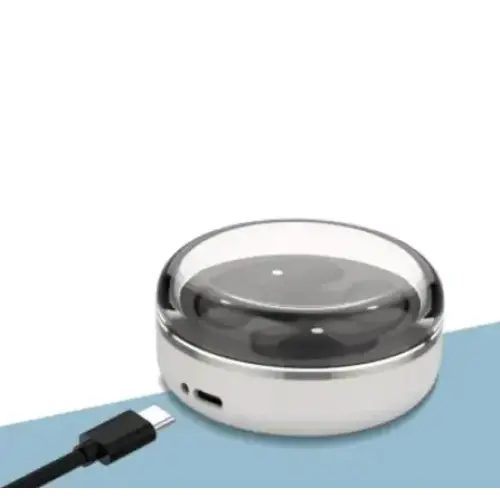 Silver circular wireless charging pad with a transparent dome cover and black usb-c cable.