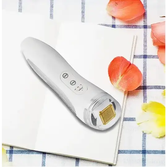 White handheld facial device with a gold-colored treatment head and three control buttons on its sleek, ergonomic body.