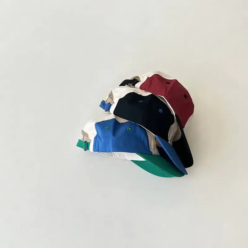 Stack of colorful baseball caps in white, black, red, blue and green with contrasting panels.