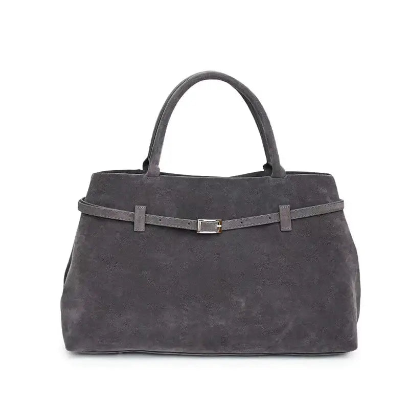 A sleek charcoal gray suede tote bag featuring a matching belt-style strap with a silver-toned buckle.