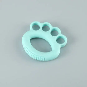 A mint green silicone baby teether shaped like a paw print with textured ridges along the bottom edge.